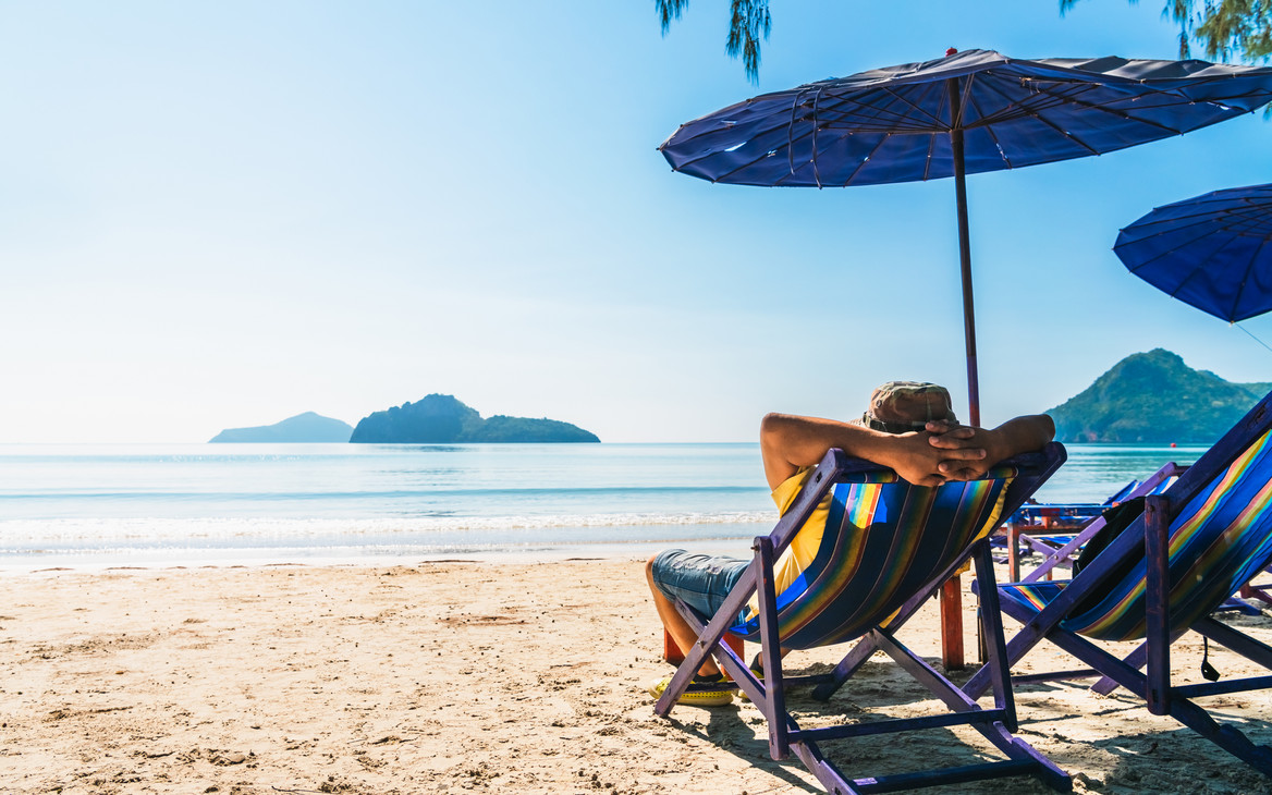 Eine Person liegt in einem Liegestuhl am Strand.