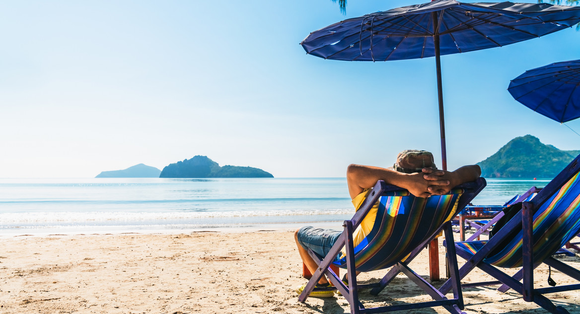 Eine Person liegt in einem Liegestuhl am Strand.
