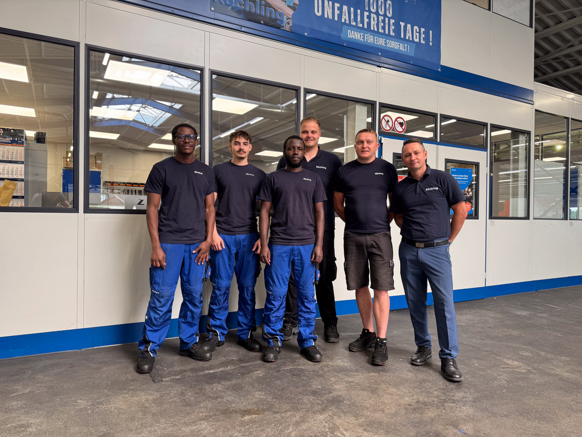 Gruppenfoto in einer Werkhalle: Ausbildungsleiter Irenaeus Jost (rechts) und Ausbilder Sven Fischer (dritter von rechts) mit Auszubildenden von Röchling Industrial am Standort Nentershausen.