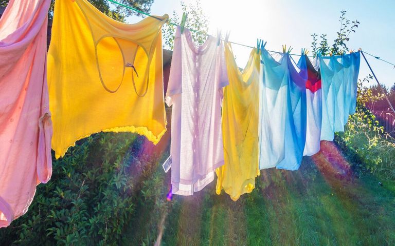 Bunte Wäsche hängt im Sonnenlicht auf der Trockenleine.