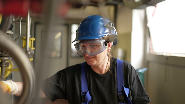 Chemikantin und Kesselwärterin prüft während eines chemischen Prozesses die Steuerungen der Anlage. 
