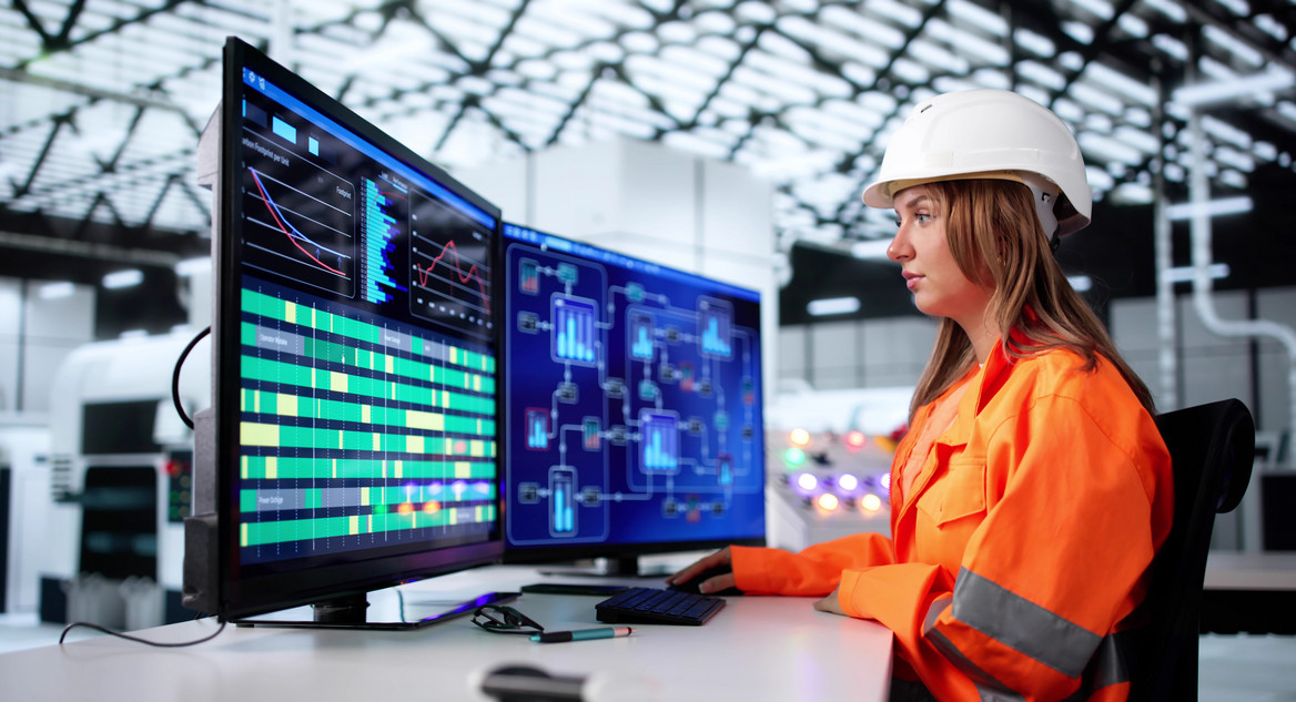 Ingenieurin beobachtet konzentriert an mehreren Monitoren die Steuerung eines Produktionsprozesses.