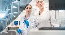 Zwei Wissenschaftlerinnen bei Analysetätigkeiten in einem modernen Labor.