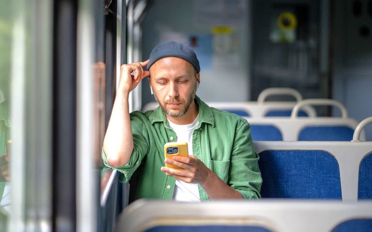 Ein junger Mann in der Bahn hört konzentriert einen Podcast.