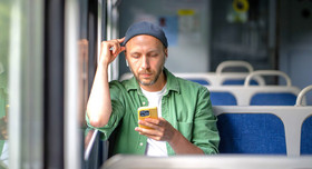 Ein junger Mann in der Bahn hört konzentriert einen Podcast.