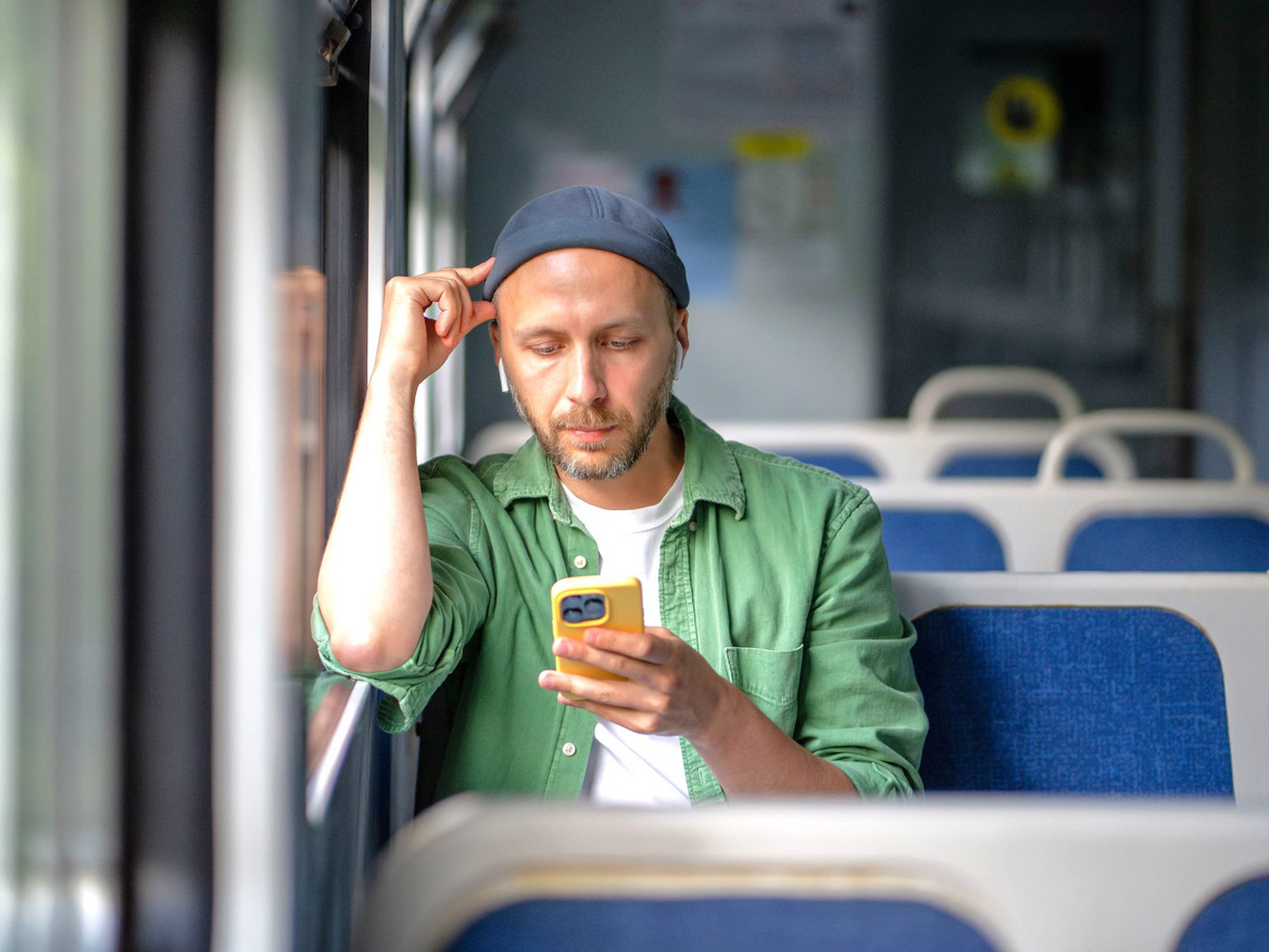 Ein junger Mann in der Bahn hört konzentriert einen Podcast.