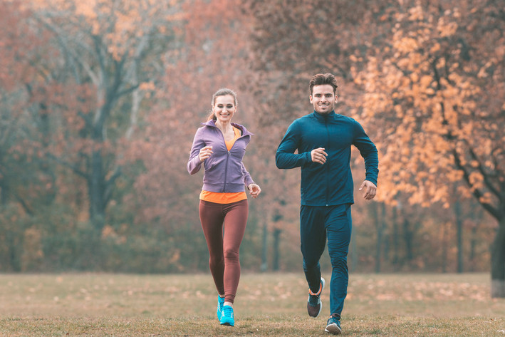 Zwei Jogger laufen zur Entspannung durch den Park.