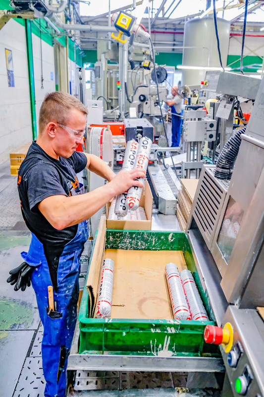 Ein Mann verpackt Klebstoff-Rollen in Kartons