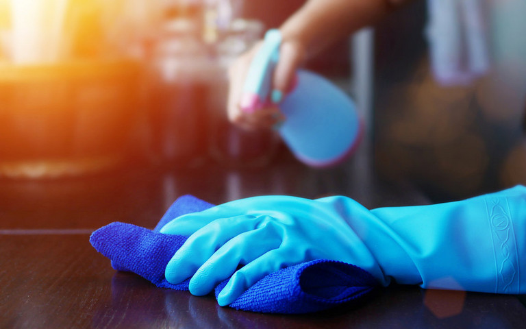 Ein Mensch mit Handschuhen benutzt Desinfektionsspray