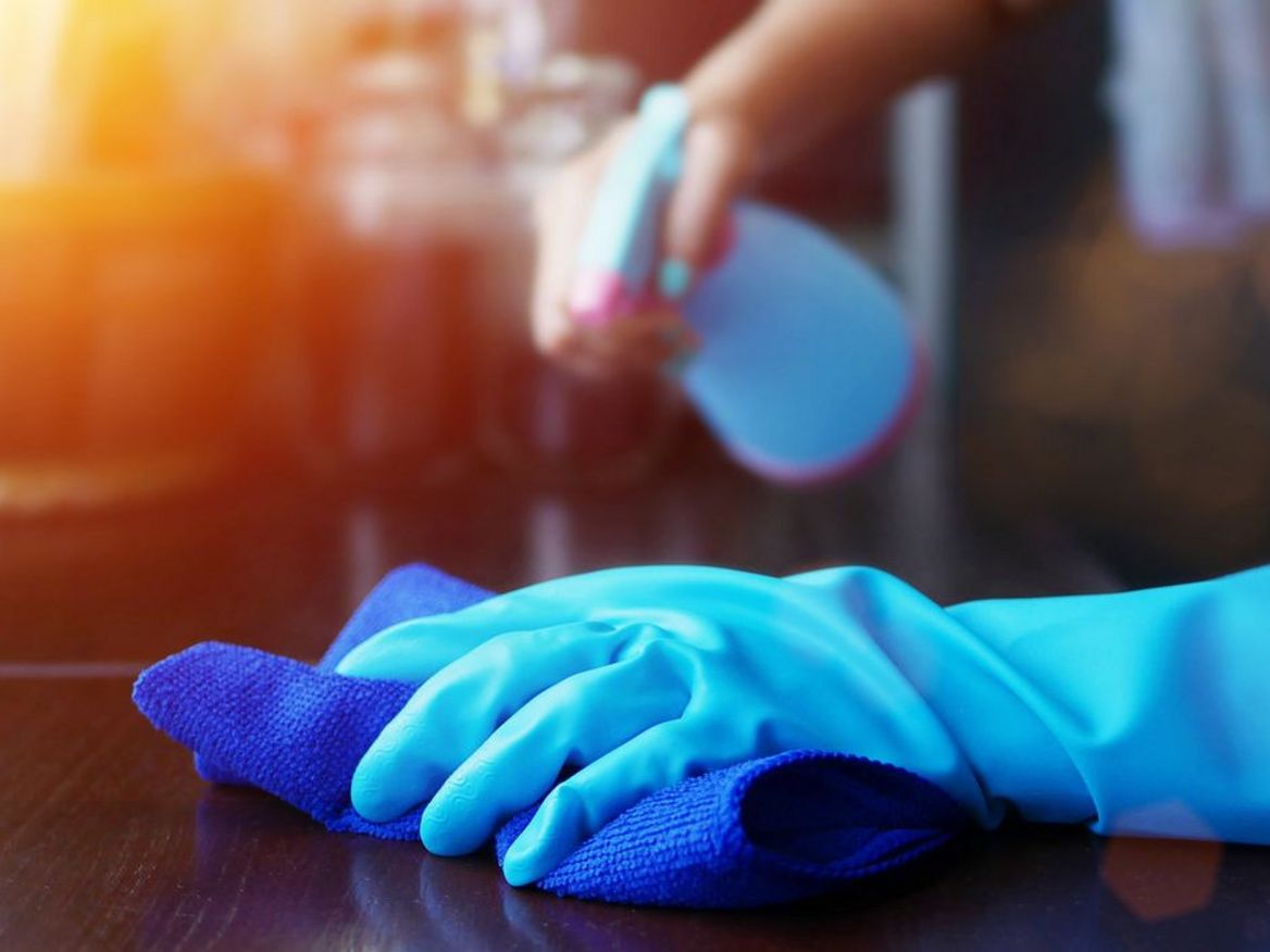 Ein Mensch mit Handschuhen benutzt Desinfektionsspray