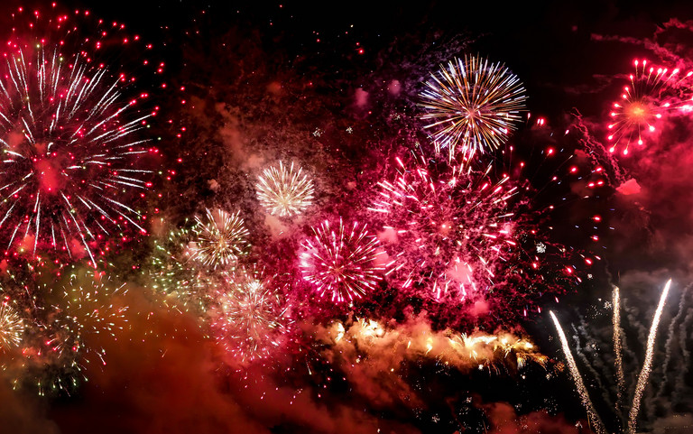 Silvesterfeuerwerk in Rot- und Goldtönen.