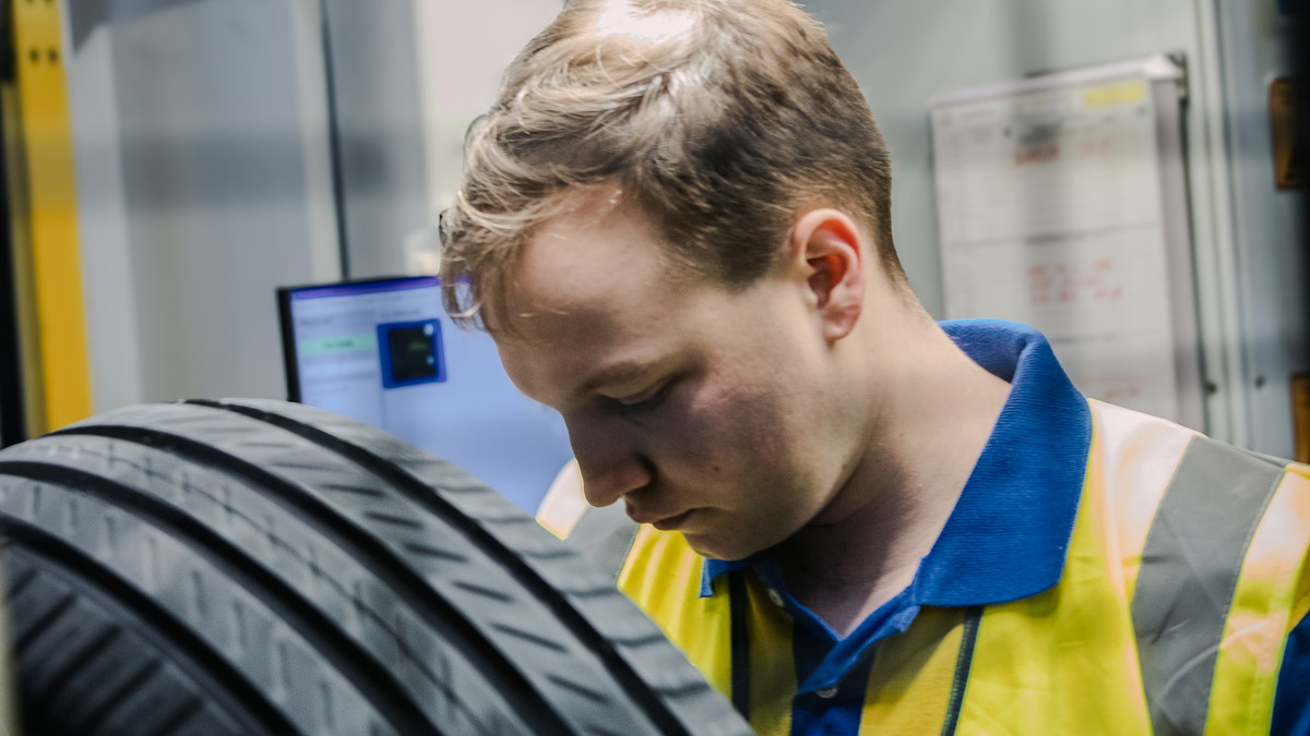 Nils Maurer checks a tire in a high-visibility vest and looks down.
