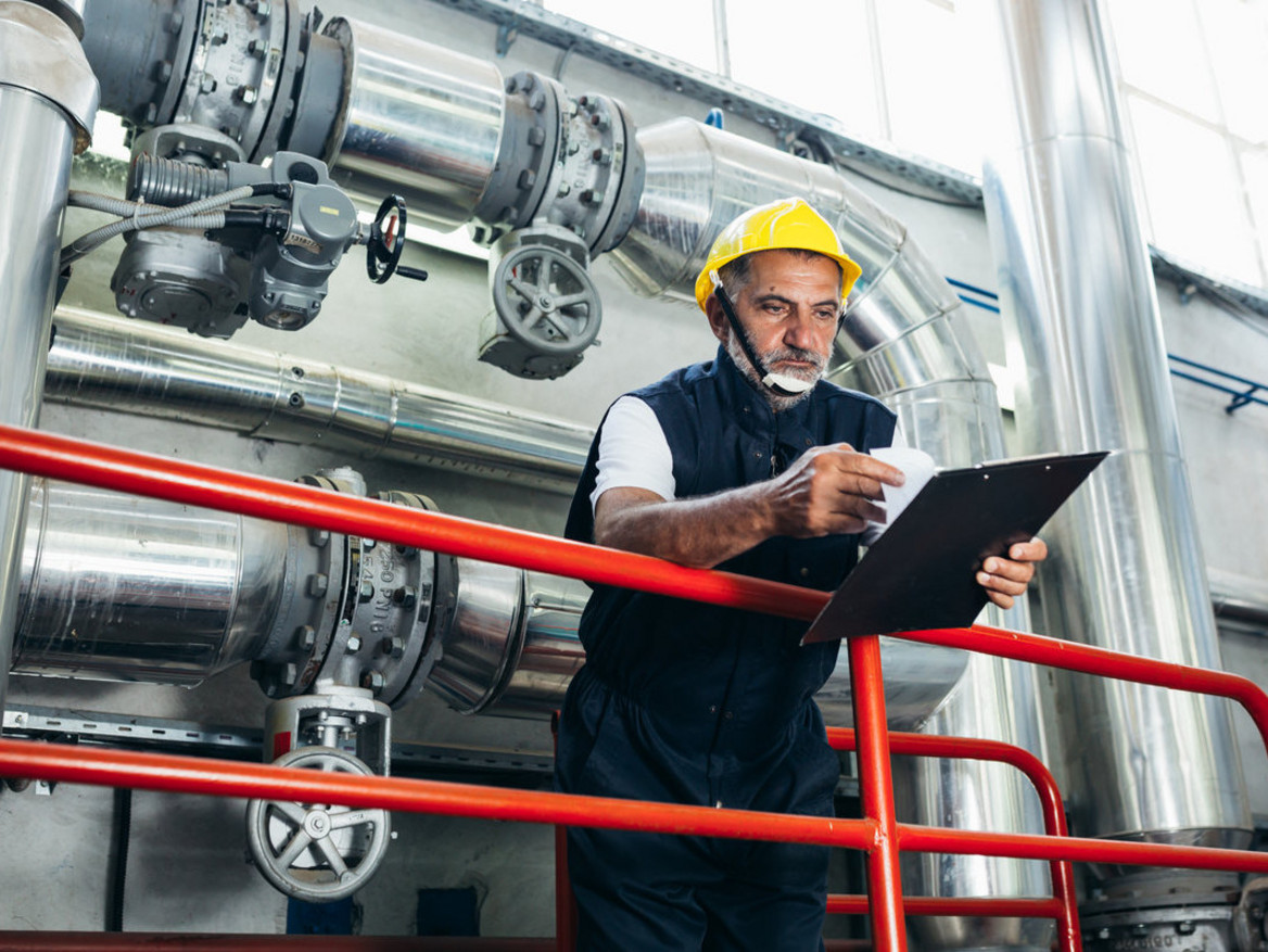 Älterer Mitarbeiter inspiziert Chemie-Anlage.