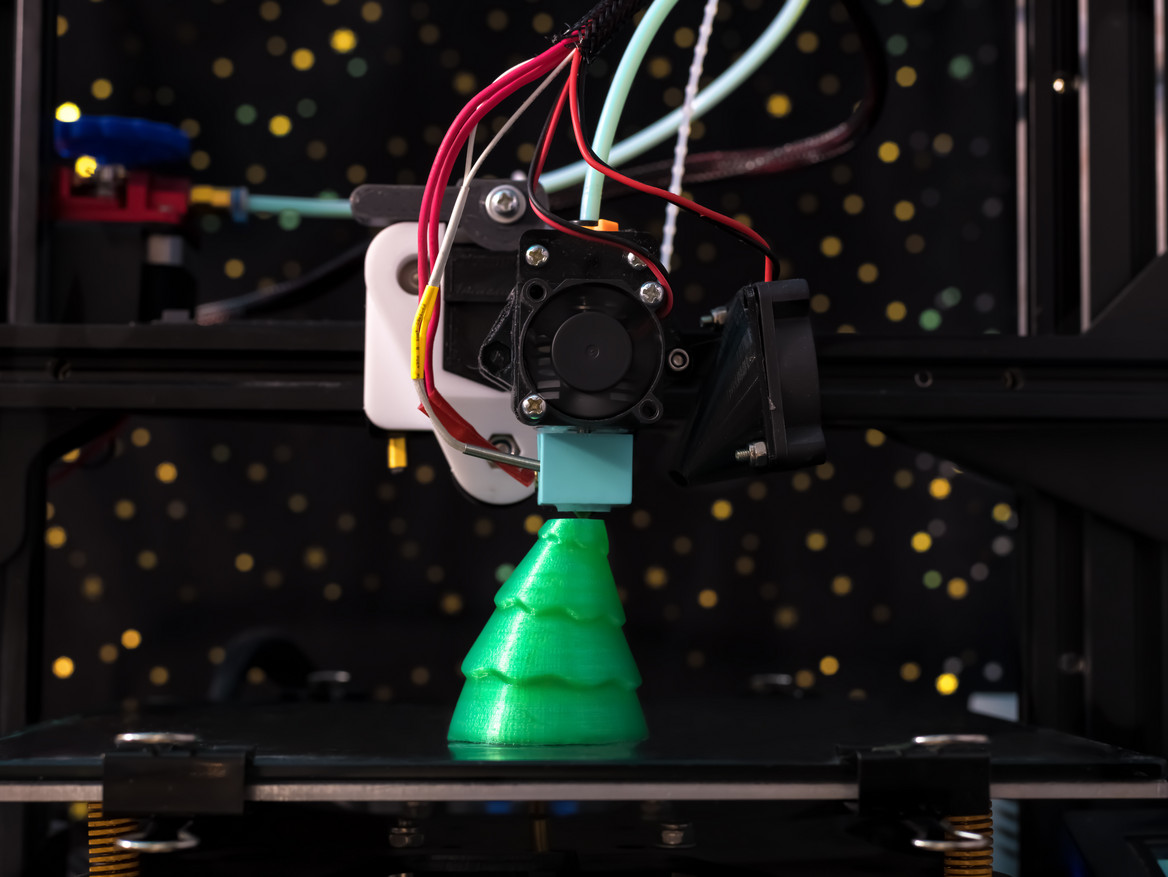 Ein grüner Weihnachtsbaum aus dem 3D-Drucker bekommt seinen letzten Schliff.