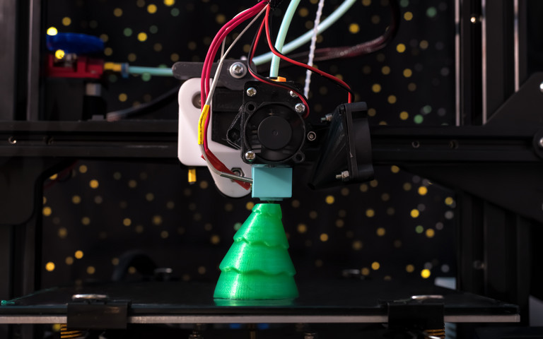 Ein grüner Weihnachtsbaum aus dem 3D-Drucker bekommt seinen letzten Schliff.