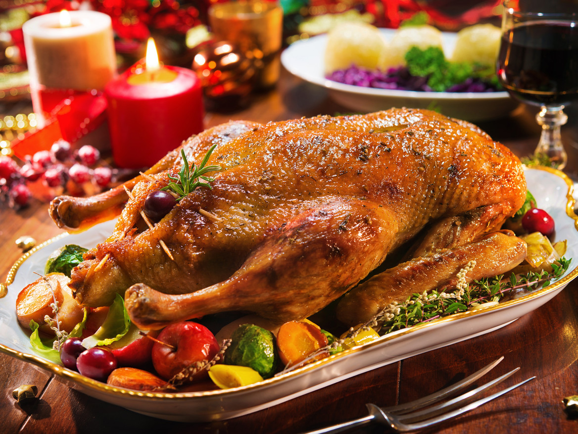 Festlich gedeckter Weihnachtstisch mit Gänsebraten, Kartoffelklößen und Rotwein.