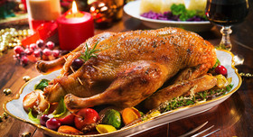 Festlich gedeckter Weihnachtstisch mit Gänsebraten, Kartoffelklößen und Rotwein.