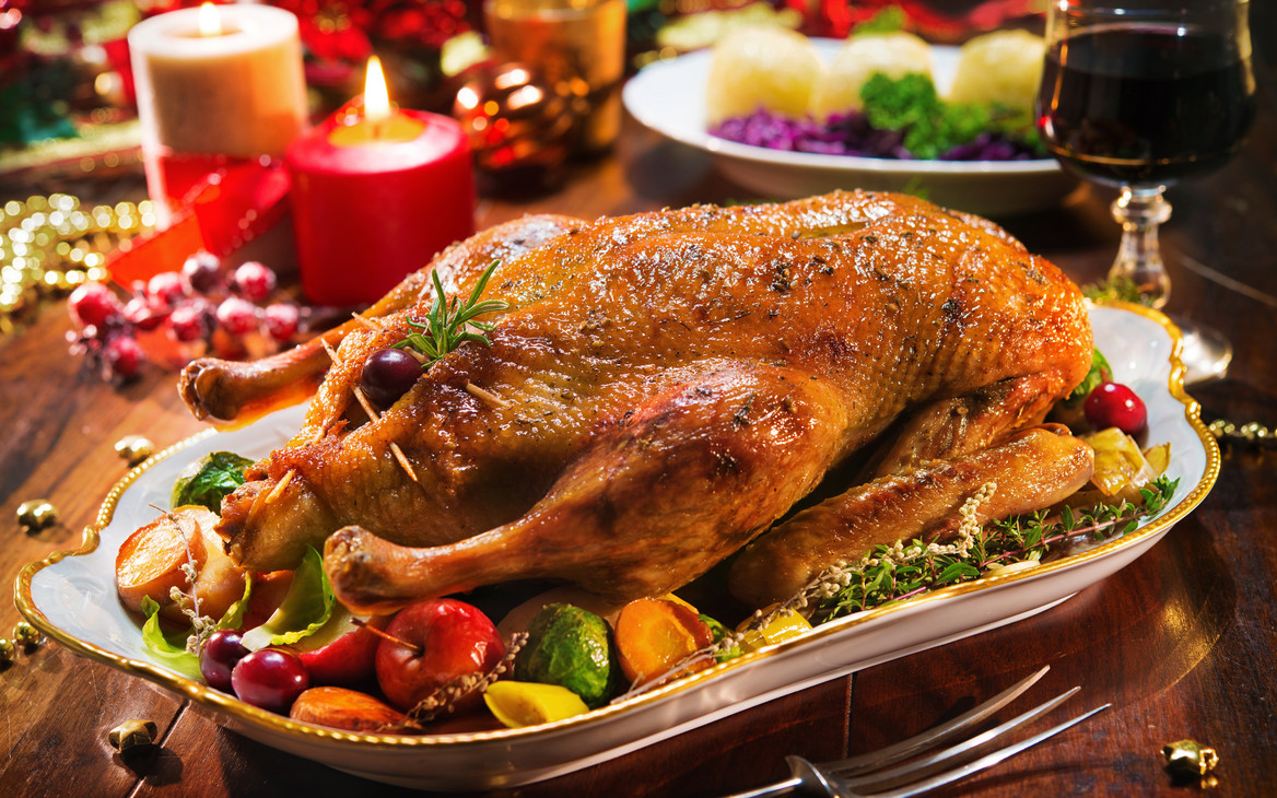 Festlich gedeckter Weihnachtstisch mit Gänsebraten, Kartoffelklößen und Rotwein.