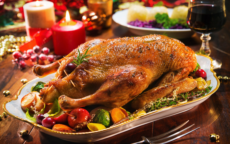 Festlich gedeckter Weihnachtstisch mit Gänsebraten, Kartoffelklößen und Rotwein.