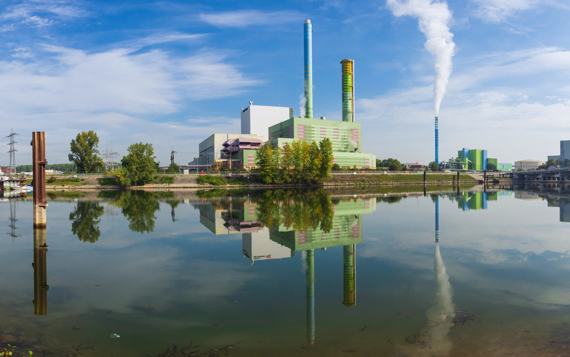 Skyline einer emittierenden Industrieanlage am Flussufer.