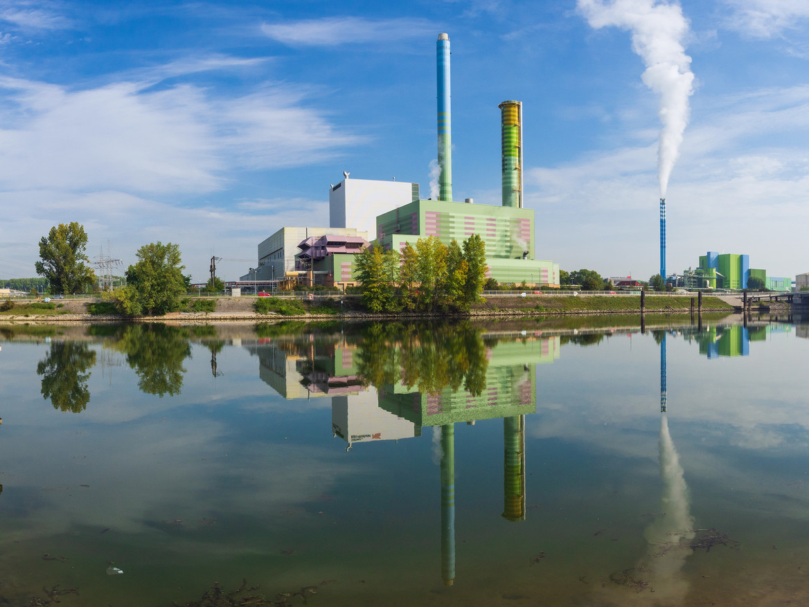 Skyline einer emittierenden Industrieanlage am Flussufer.