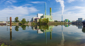 Skyline einer emittierenden Industrieanlage am Flussufer.