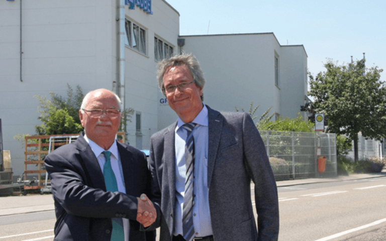 Zwei Männer drücken sich die Hand und lächeln. 