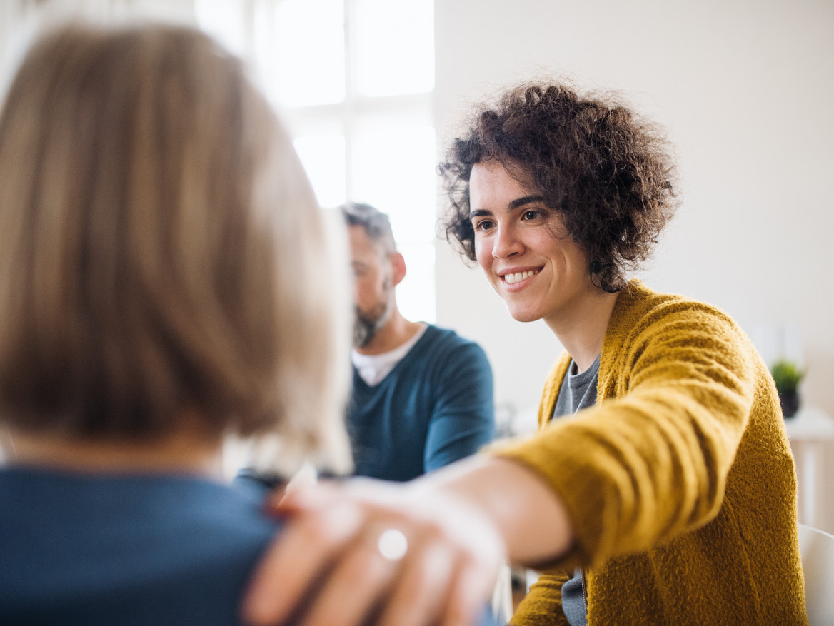 Eine Person legt einer anderen die Hand auf die Schulter. Foto: Halfpoint - stock.adobe.com