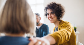 Eine Person legt einer anderen die Hand auf die Schulter. Foto: Halfpoint - stock.adobe.com