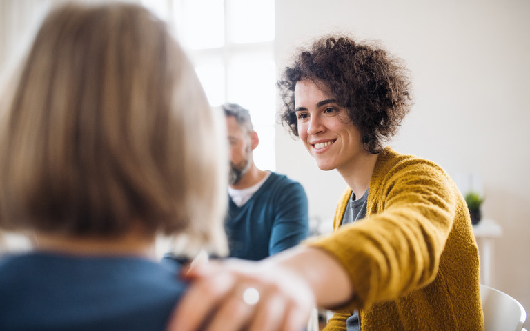 Eine Person legt einer anderen die Hand auf die Schulter. Foto: Halfpoint - stock.adobe.com