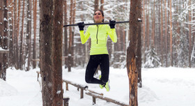 Eine Frau macht Fitnessübungen an einer Anlage im Wald.