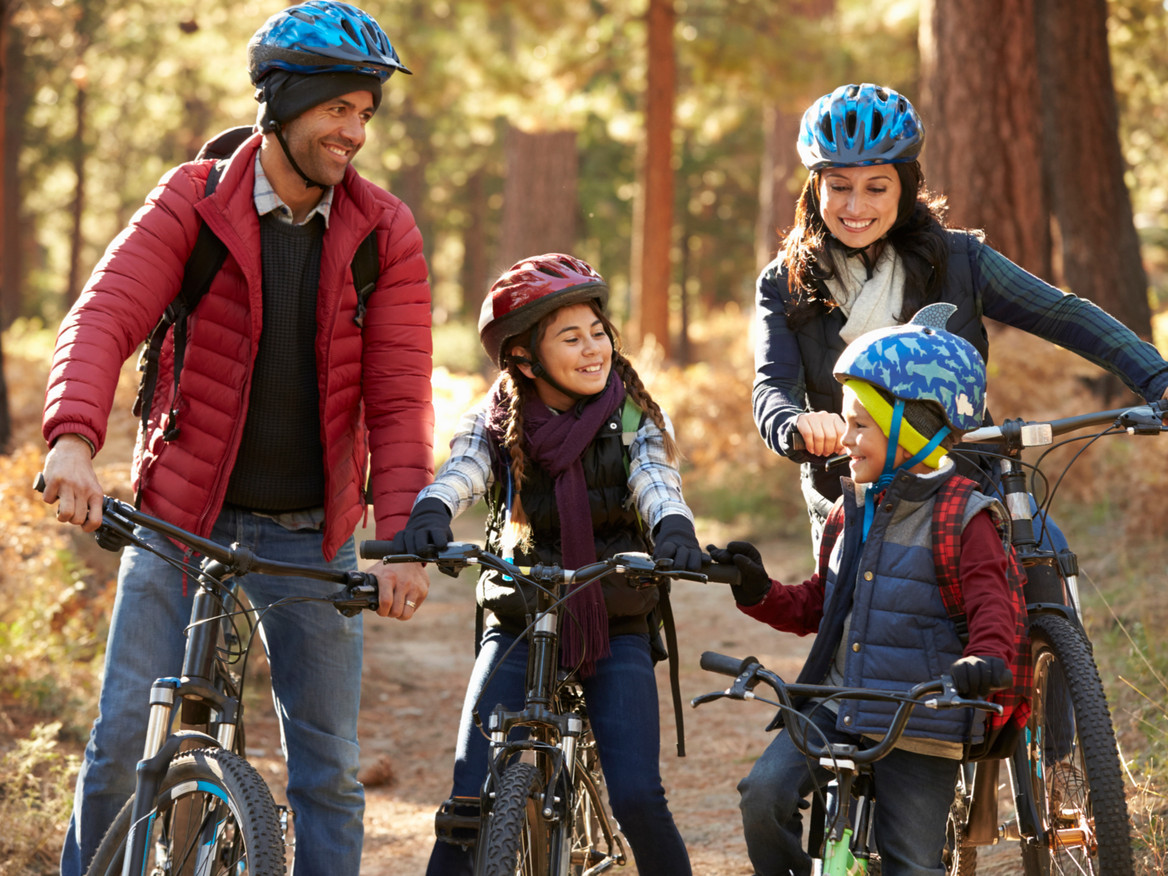 Eine vierköpfige Familie hat Spaß an ihrer Radtour durch den Herbstwald.