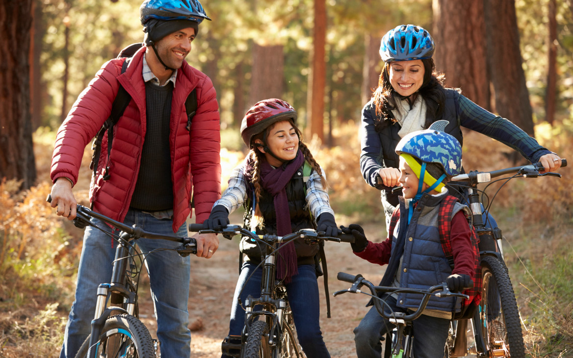 Eine vierköpfige Familie hat Spaß an ihrer Radtour durch den Herbstwald.