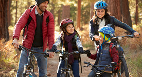 Eine vierköpfige Familie hat Spaß an ihrer Radtour durch den Herbstwald.