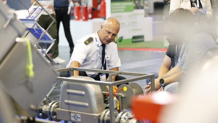 Der Chemieverband VCI präsentiert sich auf der Messe Interschutz in Hannover. Ein Experte erläutert das Exponat vor interessiertem Publikum.
