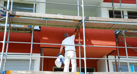 Ein Handwerker streicht eine Hauswand