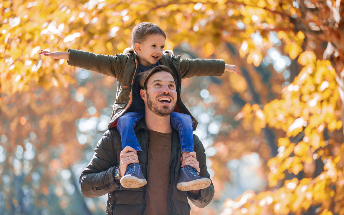 Vater und Sohn haben Spaß in einem herbstlichen Park.