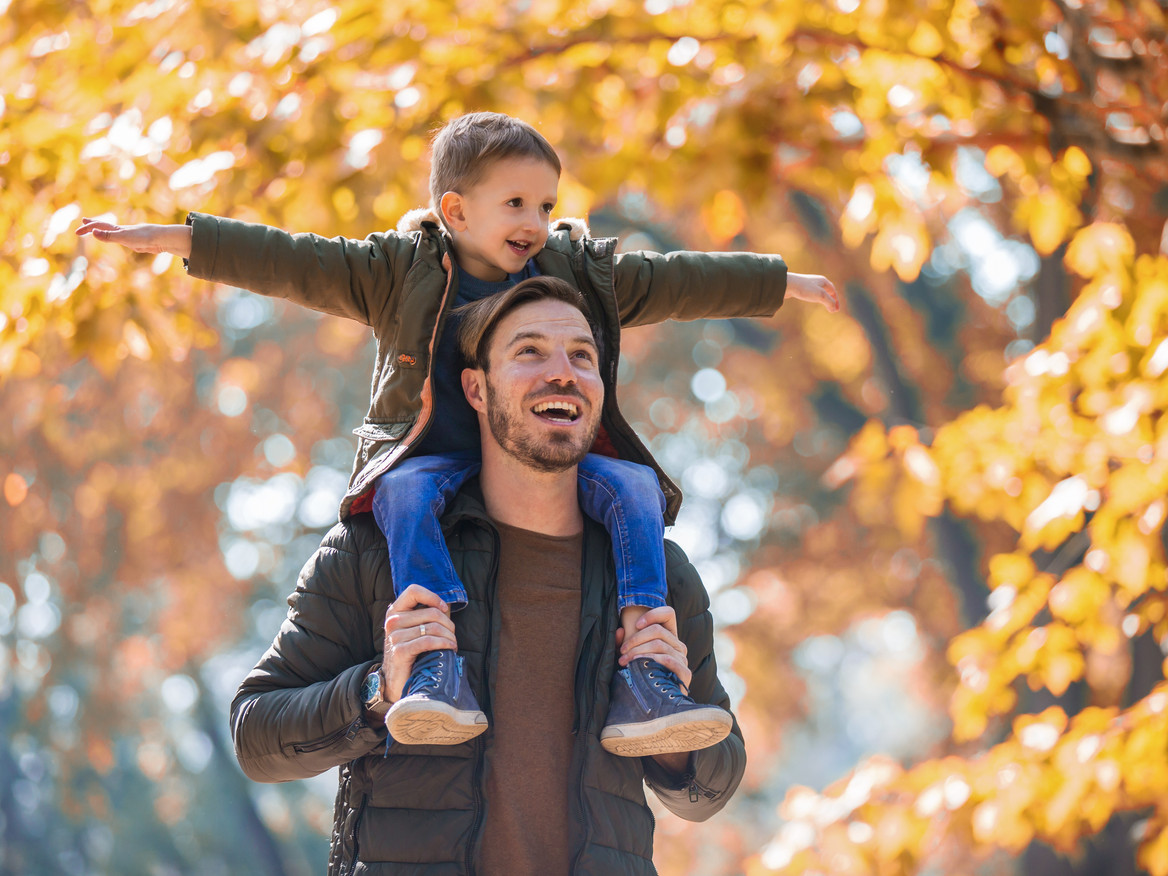 Vater und Sohn haben Spaß in einem herbstlichen Park.