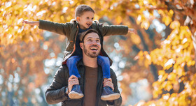 Vater und Sohn haben Spaß in einem herbstlichen Park.