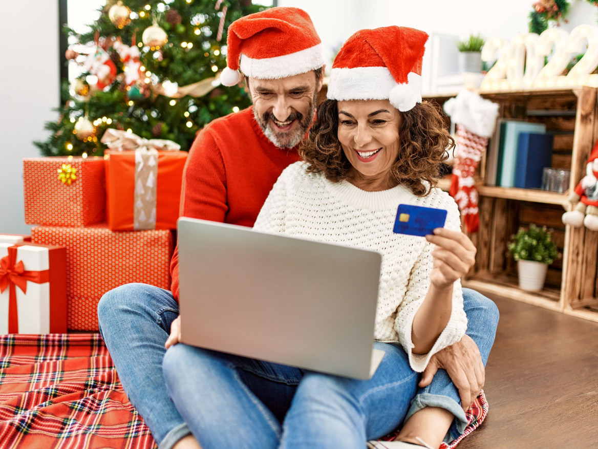 Weihnachtsfreude bei Tarifbeschäftigten Ein Paar checkt erfreut den Kontostand unterm Weihnachtsbaum: Die Jahressonderzahlung ist eingetroffen.