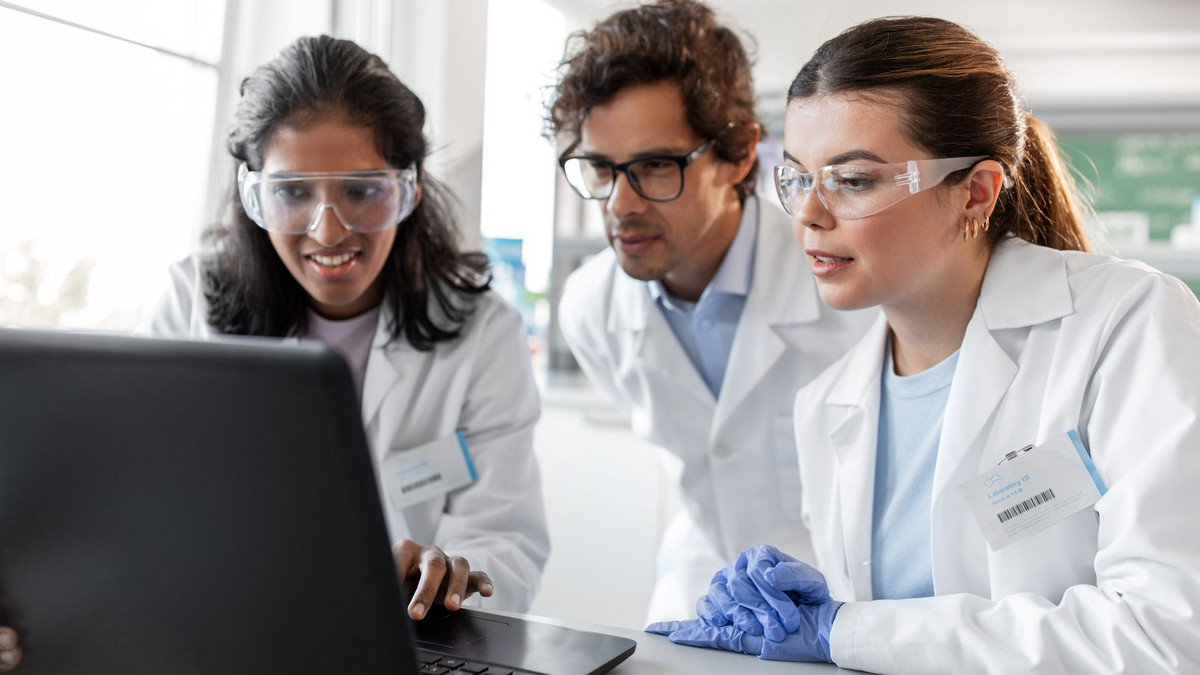 Drei Chemiefachkräfte werten zusammen am Laptop Befunde aus: Gute Teamarbeit ist wichtig in der Chemie.
