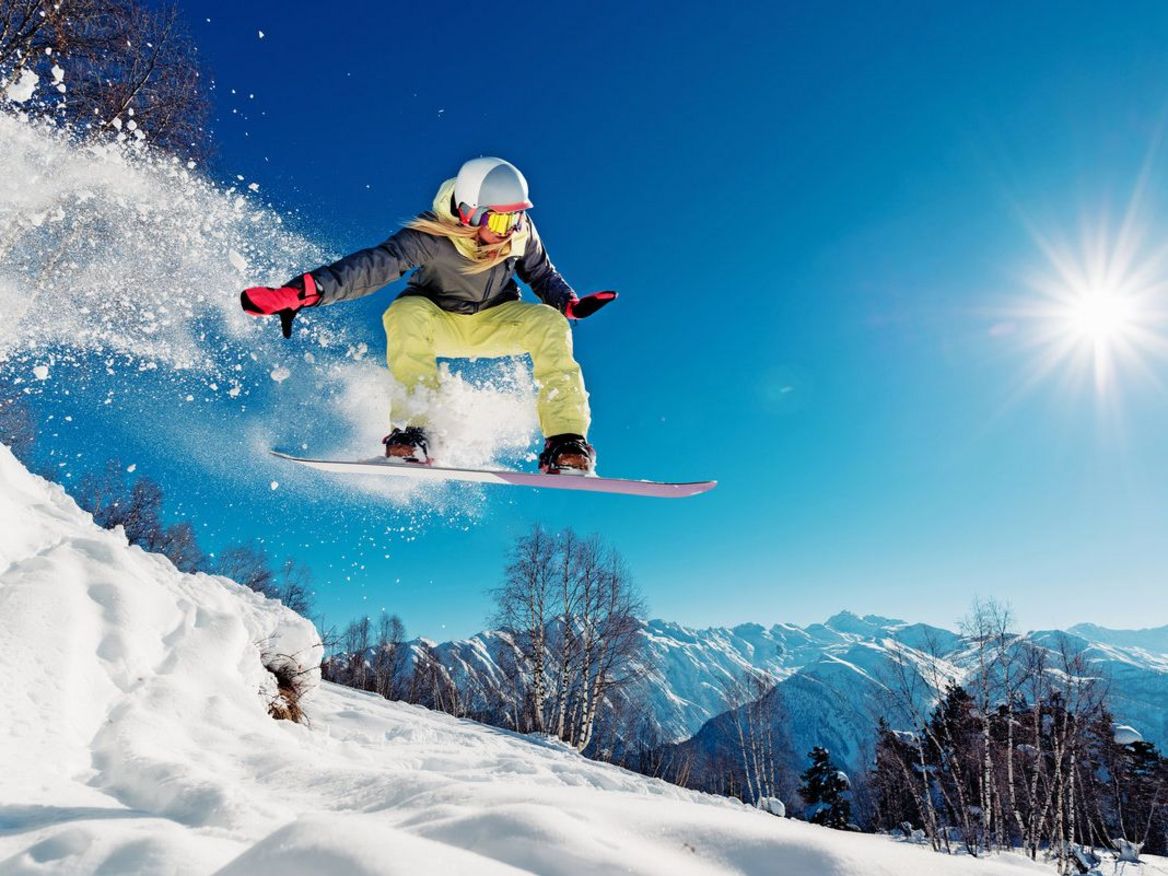 Eine Snowboarderin wagt einen rasanten Sprung in einer Schneelandschaft
