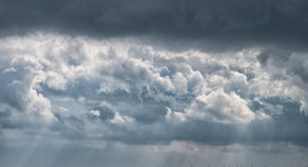 Blick auf die Nordsee, eine Skyline mit Windrädern und einen dramatischen Wolkenhimmel bei Wilhelmshaven.