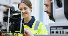 Zwei junge angehende Technikprofis bei der Steuerung von Robotikelementen in einer Lehrwerkstatt.