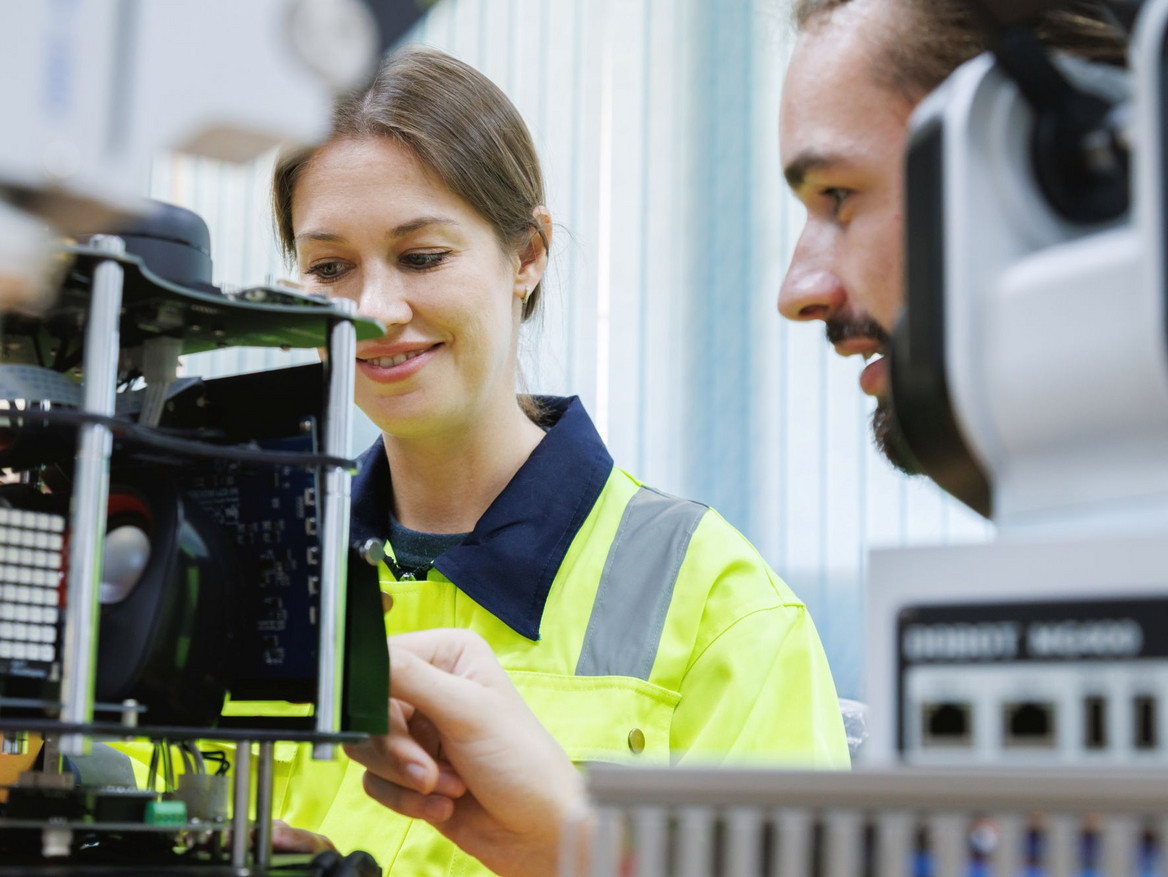 Zwei junge angehende Technikprofis bei der Steuerung von Robotikelementen in einer Lehrwerkstatt.
