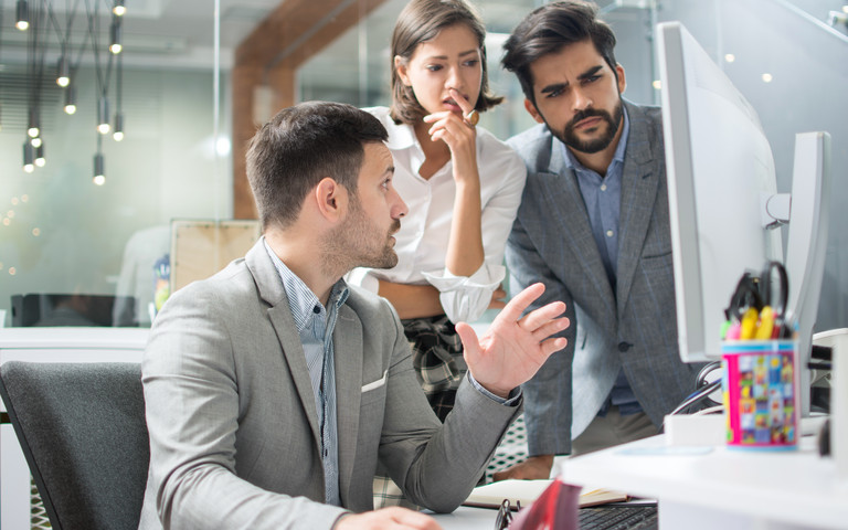 Konzentriertes Team prüft Auffälligkeiten an einem Monitor.