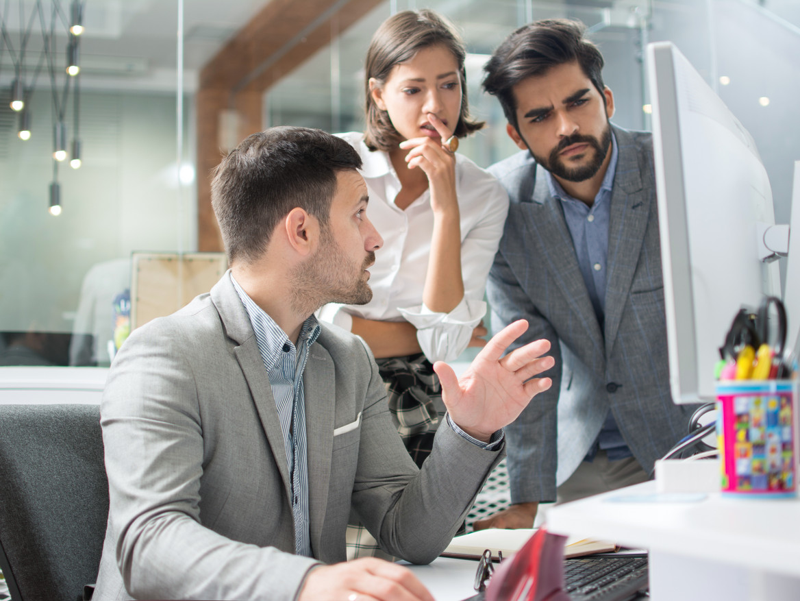 Konzentriertes Team prüft Auffälligkeiten an einem Monitor.