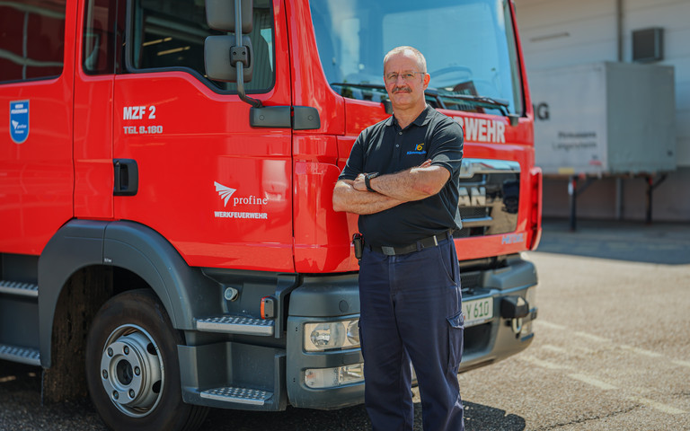 Jürgen Zipp, Leiter der Werkfeuerwehr bei der Profine Group, steht vor einem roten Feuerwehrauto. 