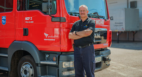 Jürgen Zipp, Leiter der Werkfeuerwehr bei der Profine Group, steht vor einem roten Feuerwehrauto. 
