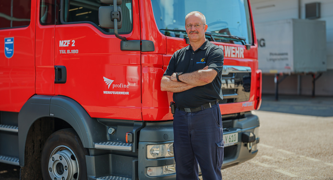 Jürgen Zipp, Leiter der Werkfeuerwehr bei der Profine Group, steht vor einem roten Feuerwehrauto. 